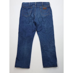 Op de afbeelding: Donkerblauwe spijkerbroek met een klassiek ontwerp met vijf zakken. De jeans heeft een bruine leren patch met de merknaam. De achterzakken hebben een klassiek stikselontwerp. De jeans liggen plat op een witte ondergrond.