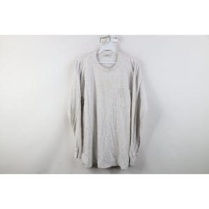 May include: A light gray long-sleeve shirt with a chest pocket. The shirt is hanging on a white hanger against a white background. The shirt appears to be made of a soft, comfortable material.