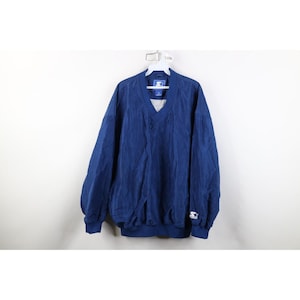 May include: A blue Starter brand pullover windbreaker with a V-neck and elastic cuffs and hem. The jacket has a Starter logo on the left sleeve and is hanging on a white hanger against a white background.