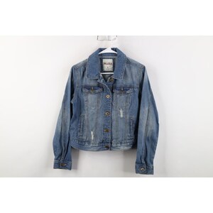 May include: A light blue denim jacket with a classic collar, button-down front, and distressed details. The jacket has long sleeves and is hanging on a white hanger. The brand name "Mudd" is visible on a tag.