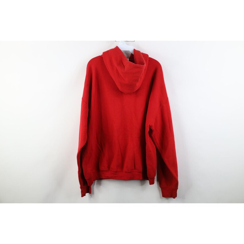 Peut inclure: Un sweat &agrave; capuche rouge uni, vu de dos. Le sweat &agrave; capuche est suspendu &agrave; un cintre blanc sur fond blanc. Le sweat-shirt a une capuche &agrave; cordon et des manches longues.