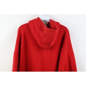 Peut inclure: Un sweat &agrave; capuche rouge, vu de dos, est suspendu &agrave; un cintre blanc. La capuche est pro&eacute;minente et le tissu semble &ecirc;tre un mat&eacute;riau doux et de poids moyen. Le sweat-shirt est de couleur rouge vif et unie.