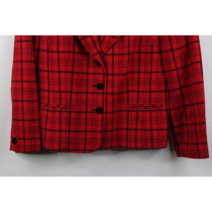 Peut inclure: Un blazer rouge avec un motif &agrave; carreaux noirs. Le blazer a un col crant&eacute;, deux poches avant et trois boutons noirs sur le devant. Les manches ont un seul bouton noir au poignet.