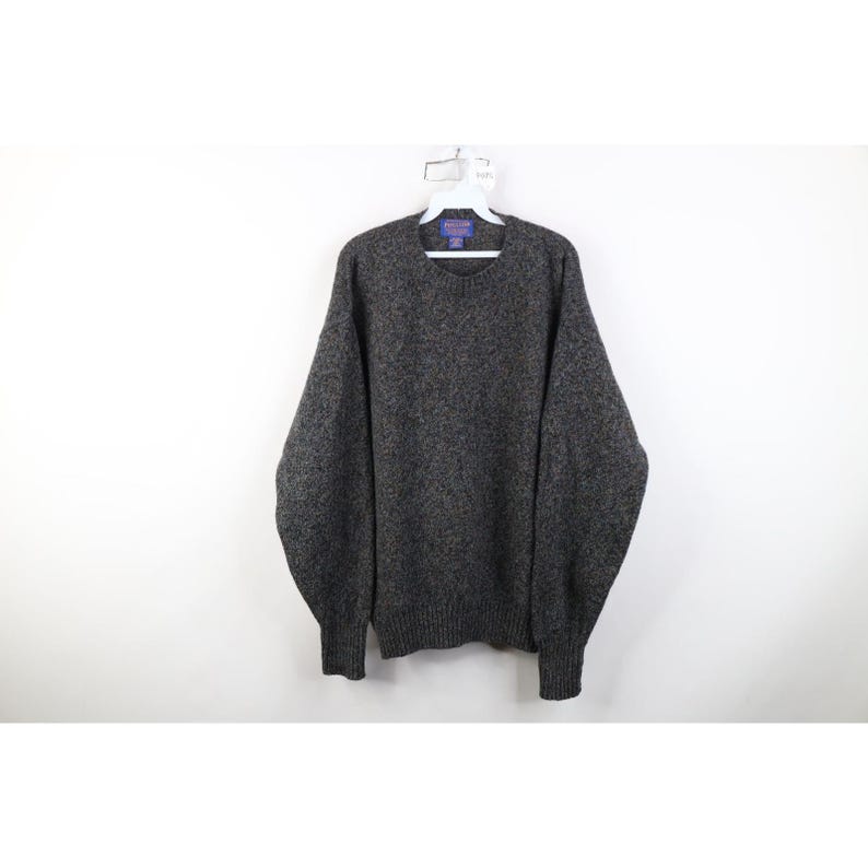 May include: A dark gray sweater with a crew neck and long sleeves hangs on a white hanger. The sweater has a speckled texture and ribbed cuffs and hem. The garment is made of a thick, warm material, perfect for cold weather.