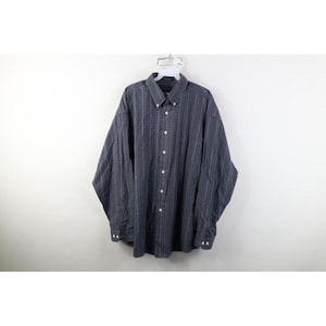 May include: A long-sleeve button-down shirt in a dark navy blue color featuring a subtle vertical pinstripe pattern. The shirt includes a classic collar, a front button placket with light-colored buttons, and buttoned cuffs on the sleeves.