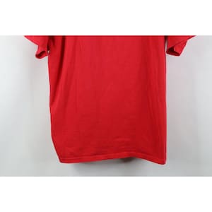 May include: A solid red t-shirt with short sleeves. The shirt is made of a soft, textured fabric. The garment is displayed against a white background.