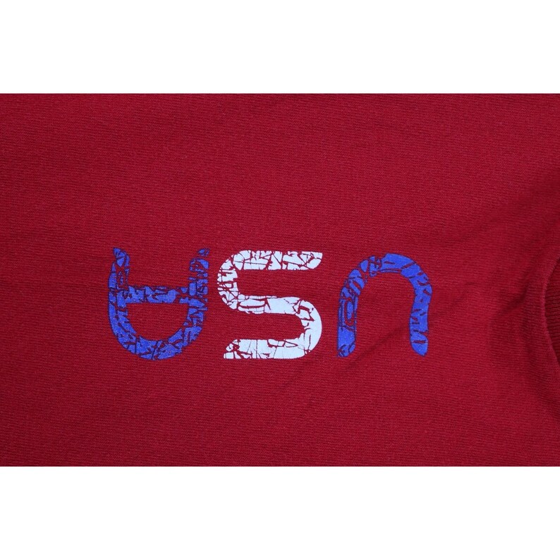 May include: A maroon fabric with the word "USA" printed across the center. The letters are white with a distressed texture, and the "U" and "A" are outlined in blue.