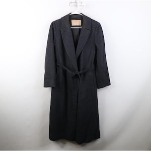 May include: A long, dark charcoal gray wool-blend coat featuring a notched lapel collar, long sleeves, and a matching fabric tie belt at the waist. The coat has a straight silhouette, a single-breasted front closure, and a visible interior brand label.
