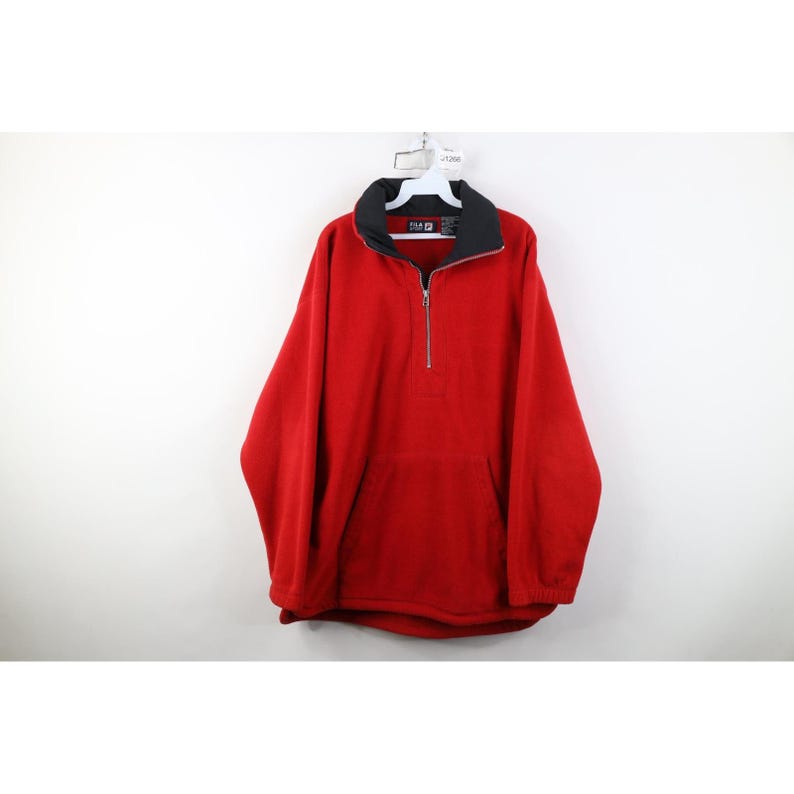 May include: A red fleece pullover with a black collar and a quarter-zip closure. The pullover has a kangaroo pocket and is hanging on a white hanger.