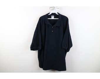 Puede incluir: Un polo de color azul marino de manga corta con cuello clásico, tapeta de dos botones y puños acanalados. La prenda se muestra en una percha de plástico blanca sobre un fondo blanco liso, exhibiendo un diseño sencillo y funcional.