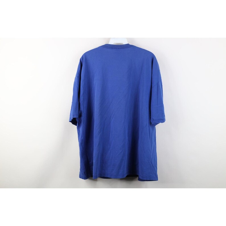 May include: A solid blue t-shirt with short sleeves. The shirt is made of a soft material and hangs on a white hanger against a white background. The shirt is a medium size.
