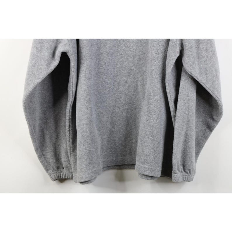 May include: A heather gray fleece pullover sweatshirt. The long sleeves have elastic cuffs, and the bottom hem is also elastic. The fabric has a soft, textured appearance. The sweatshirt is a casual style.