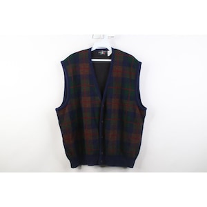 May include: A button-down vest with a plaid pattern in shades of navy blue, green, and burgundy. The vest has a V-neck and a dark blue trim. The garment is displayed on a white hanger against a white background.