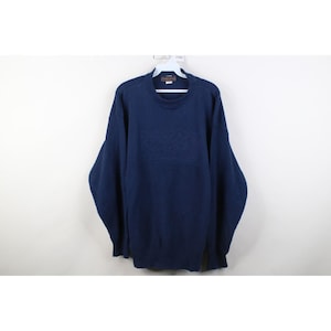 May include: A navy blue sweater with a crew neck and long sleeves. The sweater is hanging on a white hanger against a white background. The sweater has a textured design on the chest.