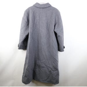 May include: A gray, full-length coat with a classic design. The coat features a notched collar, long sleeves, and a button closure. The back of the coat is visible, showing a center seam and a tailored fit. The coat is made of a soft, wool-like material.