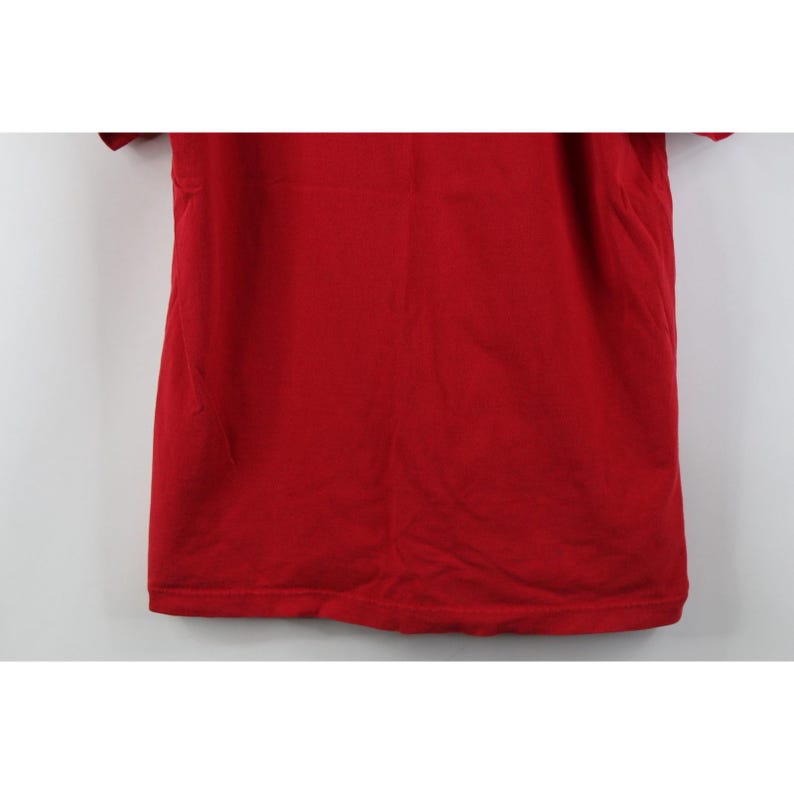 May include: A solid red t-shirt with short sleeves. The shirt is made of a soft material and has a simple, classic design. The fabric appears slightly textured.