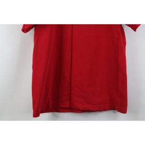 May include: A solid red t-shirt with short sleeves. The shirt is made of a soft material and has a simple, classic design. The shirt is a vibrant shade of red, perfect for casual wear.