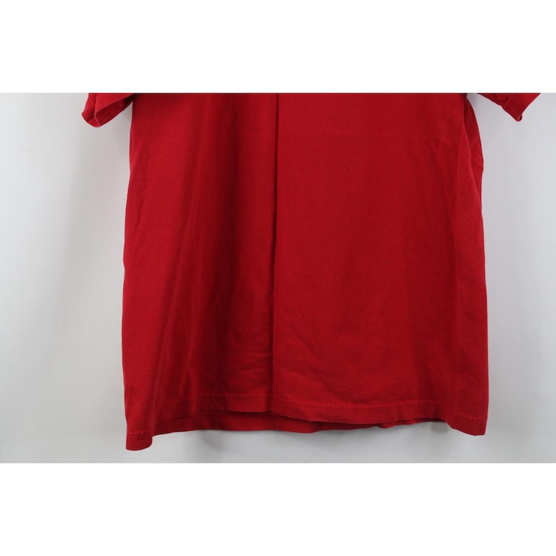 May include: A solid red t-shirt with short sleeves. The shirt is made of a soft material and has a simple, classic design. The shirt is a vibrant shade of red, perfect for casual wear.