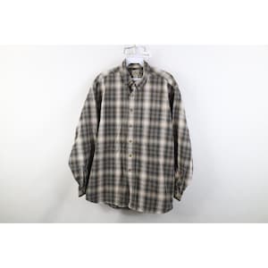 May include: A white ceramic mug with a black handle and the text "But First, Coffee" in a bold, black font. The mug is filled with a dark liquid, likely coffee, and sits on a light-colored surface.