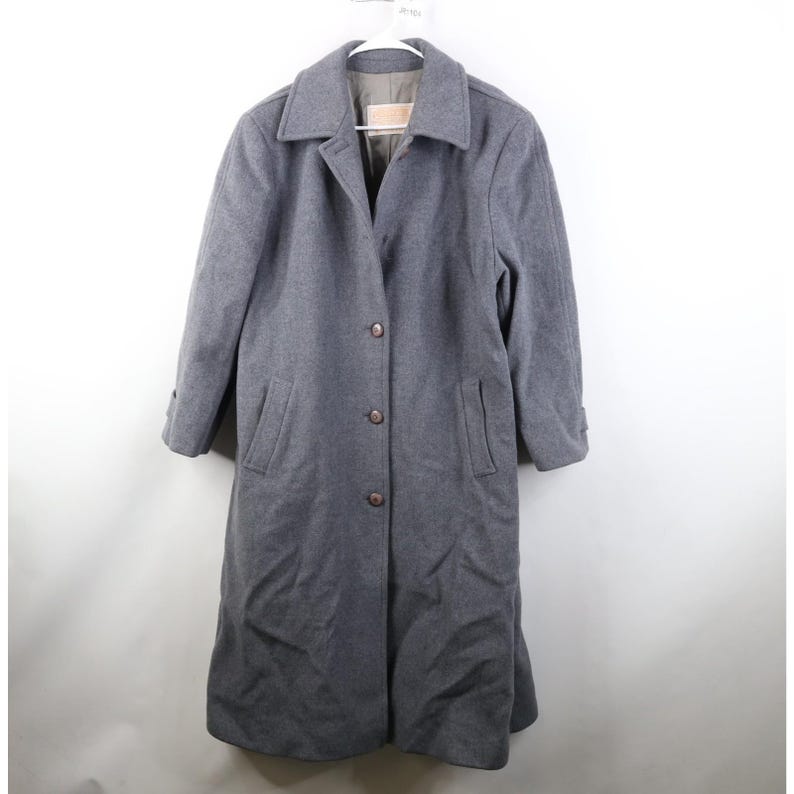 May include: A gray wool coat with a classic design. The coat features a collared neckline, button-down closure, and two front pockets. The coat is hanging on a white hanger.