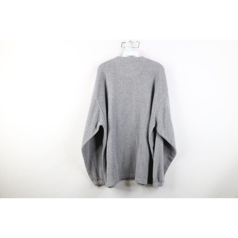 May include: A heather gray sweatshirt hangs on a white hanger against a white background. The long-sleeved sweatshirt has a crew neck and ribbed cuffs and hem. The fabric appears to be a soft, fleece-like material.
