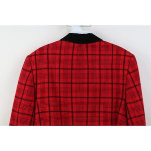 Peut inclure: Blazer &agrave; carreaux rouges et noirs avec un col noir. Le blazer est suspendu &agrave; un cintre blanc. Le motif &agrave; carreaux est un design classique, avec une base rouge audacieuse et des lignes noires.