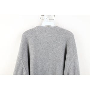 May include: A light gray sweater with a crew neck and long sleeves. The sweater is made of a soft, knitted material and is hanging on a white hanger against a white background.