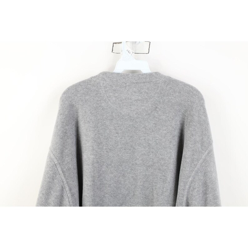 May include: A light gray sweater with a crew neck and long sleeves. The sweater is made of a soft, knitted material and is hanging on a white hanger against a white background.