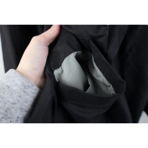May include: Close-up of a black jacket pocket with a light gray interior. The pocket is open, revealing the lining. The jacket appears to be made of a smooth, possibly water-resistant material.