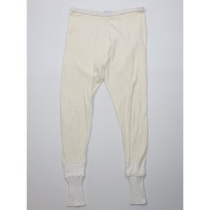 May include: Cream thermal underwear bottoms with a white waistband and cuffs. The long johns are made of a soft, ribbed fabric. The cuffs at the ankles are a contrasting white colour.