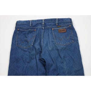 Op de afbeelding: Blauwe denim jeans met het Wrangler-logo op de achterzak. De jeans hebben een klassiek ontwerp met vijf zakken en een rechte pijp. De jeans zijn gemaakt van een duurzame denim stof.