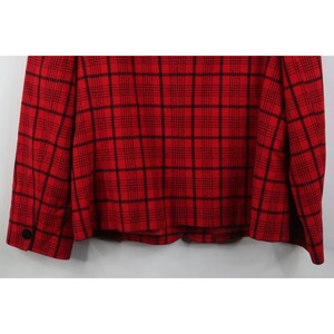 Peut inclure: Un blazer rouge avec un motif &agrave; carreaux noirs. Le blazer a des manches longues et un seul bouton noir sur le poignet. Le tissu a une texture tiss&eacute;e.