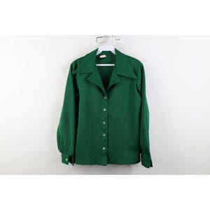May include: A solid dark green long-sleeve button-down shirt featuring a wide pointed collar, a front button placket with five visible buttons, and cuffs with single buttons. The shirt has a smooth texture and a straight hemline.