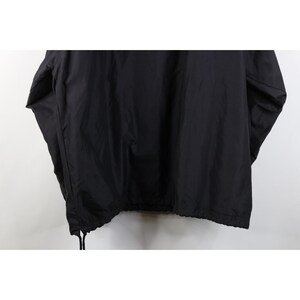 May include: A black coach jacket with a drawstring hem. The jacket is made of a smooth, possibly nylon, material. The sleeves are long and the jacket appears to be unlined. The hem has a drawstring for adjustment.