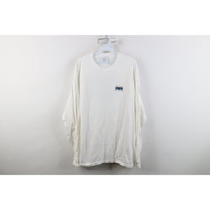 以下が含まれることがあります： 左胸に小さなグラフィックが施された白い長袖Tシャツ。グラフィックには、青い山のイラストの上に赤い文字で「Lost Coast」、その下に小さな黒い文字で「Brewery & Smokehouse」と記されています。