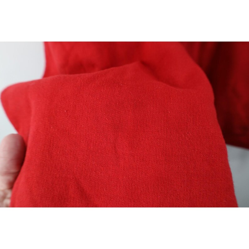 Peut inclure: Gros plan sur un tissu rouge vif, probablement une partie d'un v&ecirc;tement. La mati&egrave;re semble &ecirc;tre un tricot doux, avec une texture subtile visible. La couleur est un rouge uni et satur&eacute;, remplissant le cadre de sa teinte audacieuse.