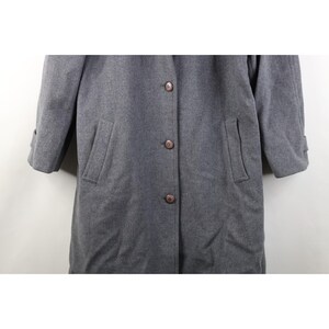 May include: A gray, button-down coat with two front pockets and buttoned cuffs. The coat has a classic design and is made of a soft, textured fabric. The coat is a versatile outerwear piece.