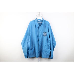 May include: A light blue button-up jacket with two front pockets and a drawstring hem. The jacket has a collar and long sleeves. The text "CITIZENS" and "STRONG" is printed on the left chest area in black.