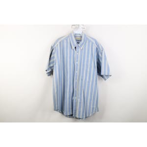 May include: A short-sleeved button-down shirt with vertical stripes in light blue and off-white. The shirt has a button-down collar and a chest pocket. The shirt is hanging on a white hanger against a white background.