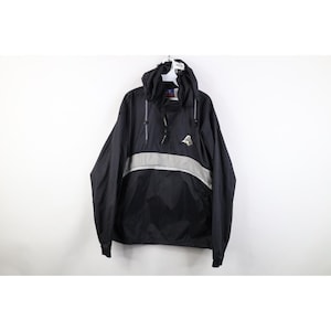 May include: Black hooded anorak jacket with a silver stripe across the chest. The jacket features a drawstring hood and a small logo on the chest. It is hanging on a white hanger against a white backdrop.