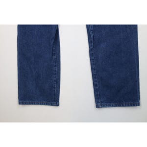 May include: Close-up of two legs of blue denim jeans. The jeans are a medium wash with visible texture and slight fading. The hems are straight and the fabric appears to be sturdy.