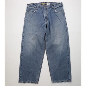 May include: Light blue denim jeans with a classic five-pocket design. The jeans have a straight leg cut and a faded wash, with visible wear and tear around the pockets and hems. The jeans are a medium-weight denim.