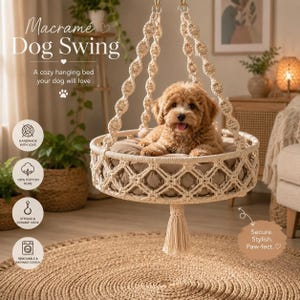 May include: A cream-colored macramé dog swing featuring a round base with a woven diamond pattern, suspended by thick braided ropes. A small, light brown curly-haired puppy sits inside on a soft, round, beige cushion. A tassel hangs below.