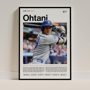 May include: A framed poster featuring Shohei Ohtani in a baseball uniform, holding a bat. The poster has the name "Ohtani" in large black letters, with the number "17" in the upper right corner. The poster includes text about Ohtani's achievements.