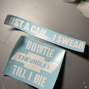 Puede incluir: Dos calcomanías de vinilo azul claro con texto blanco. Una dice "JUST A CAM... I SWEAR". La otra presenta el logotipo de Chevrolet y las palabras "BOWTIE CHEVROLET TILL I DIE". Las calcomanías están sobre una superficie gris.