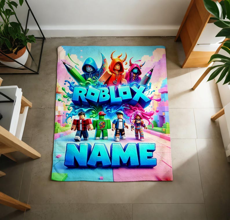 May include: A rectangular fleece blanket featuring a vibrant Roblox-themed graphic. The design displays various blocky character figures, colorful paint splashes, and the bold blue text ROBLOX and NAME printed in a large, stylized font.