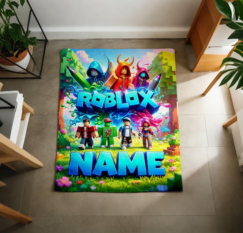 May include: A rectangular blanket featuring a vibrant Roblox-themed graphic with blocky characters, colorful splashes, and the text ROBLOX NAME in large blue letters. The design includes a grassy landscape with trees and flowers.