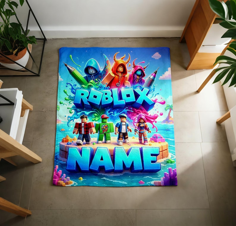 May include: A rectangular blanket featuring a vibrant Roblox-themed graphic with the text ROBLOX and NAME in bold blue letters. The design includes four blocky character figures standing on a sandy island surrounded by blue water and colorful splashes.