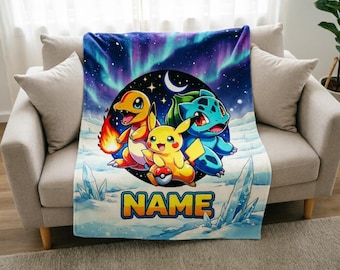 May include: A plush blanket featuring a colorful illustration of three cartoon characters, including a yellow Pikachu, set against a backdrop of a starry night and aurora borealis. The blanket has the word "NAME" in large, yellow letters.