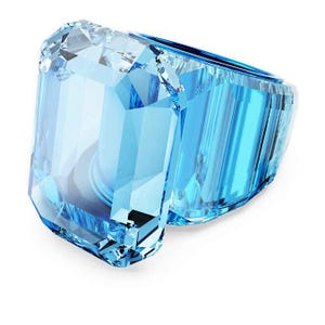 May include: A large, light blue gemstone ring with an emerald cut. The ring features a faceted design, reflecting light and creating a sparkling effect. The band is also light blue and appears to be made of the same material as the gemstone.